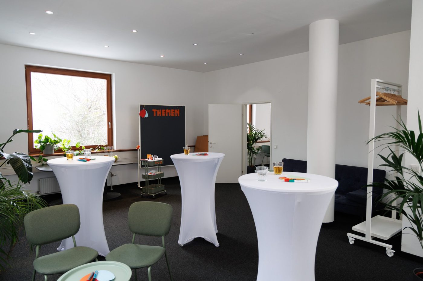 Nebenraum mit Stehtischen und Garderobe